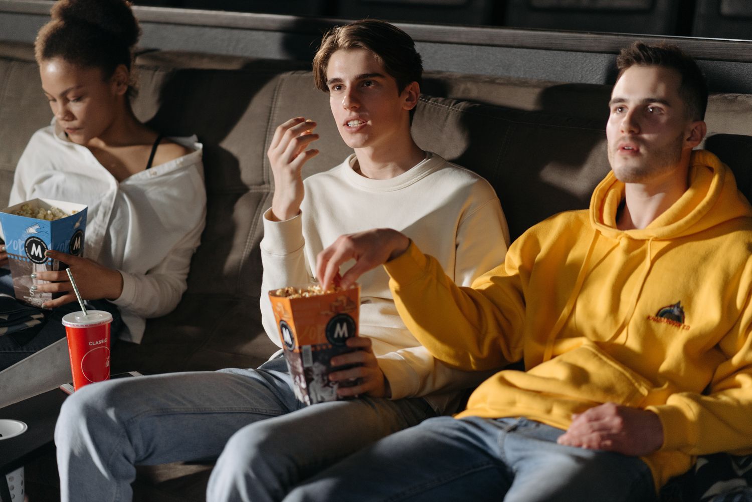 Three people sharing popcorn during a film night.