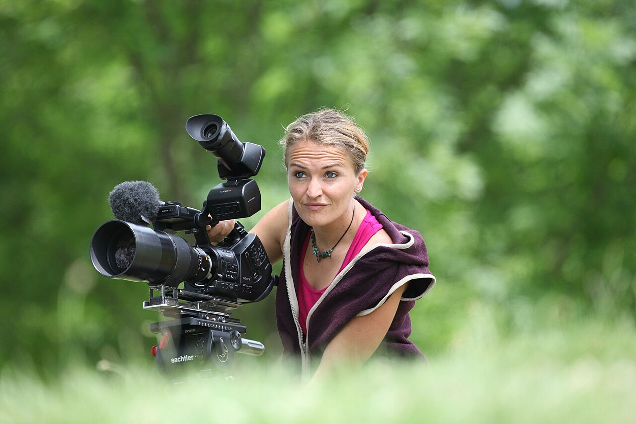 Camera operator filming outdoors.