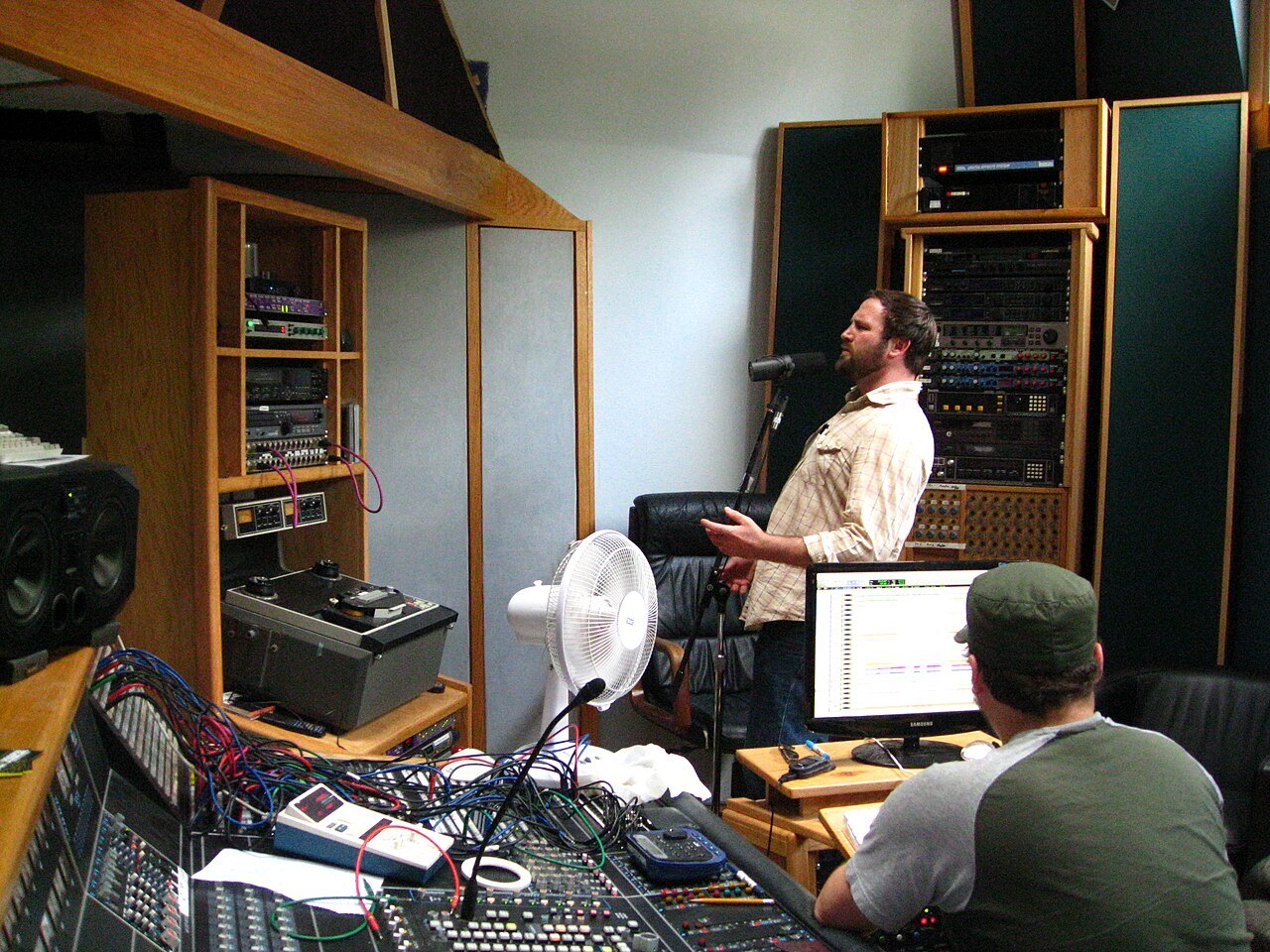 Vocal recording with a microphone and engineer in a studio.