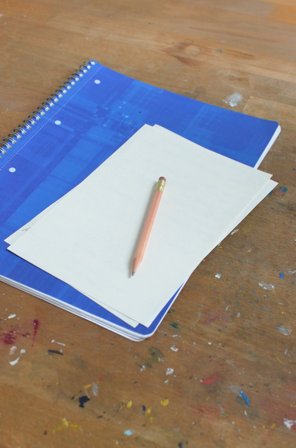 Pencil and blank sheets of paper on a spiral notebook.