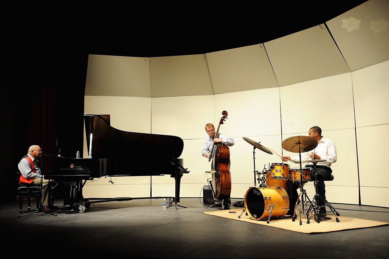 Jazz trio with piano, double bass and drums on stage.