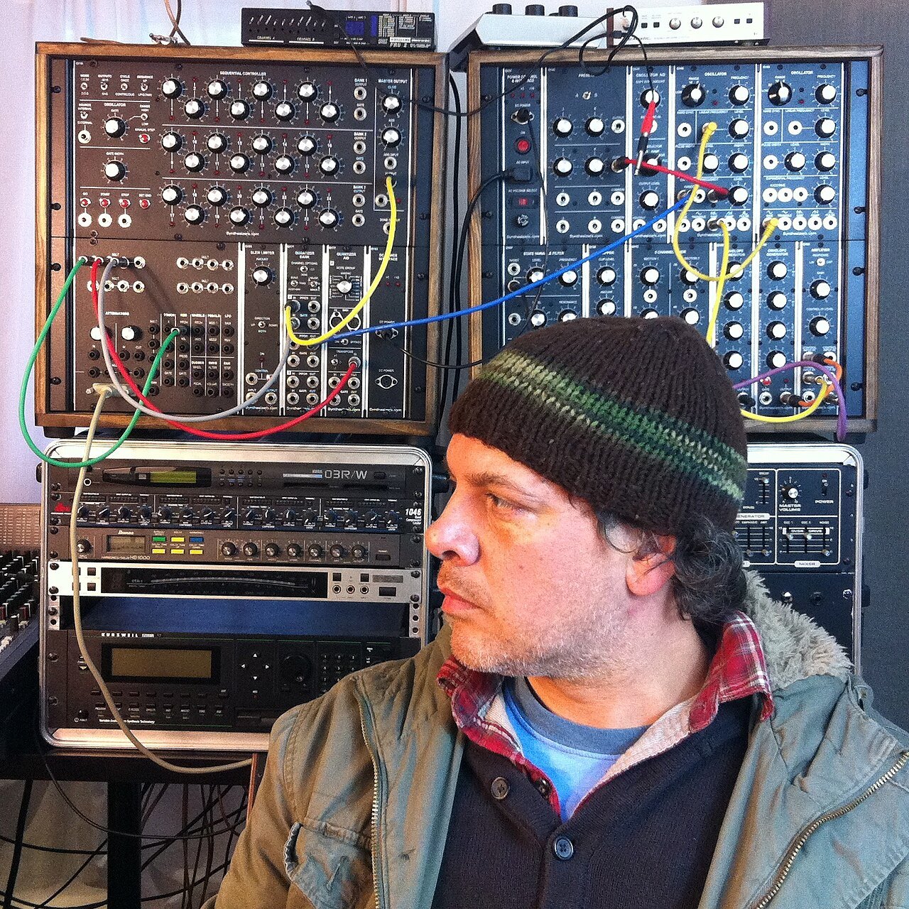 Musician in front of a modular synthesizer in a studio.