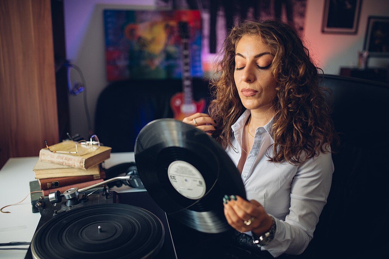 A person holding a record beside a turntable.