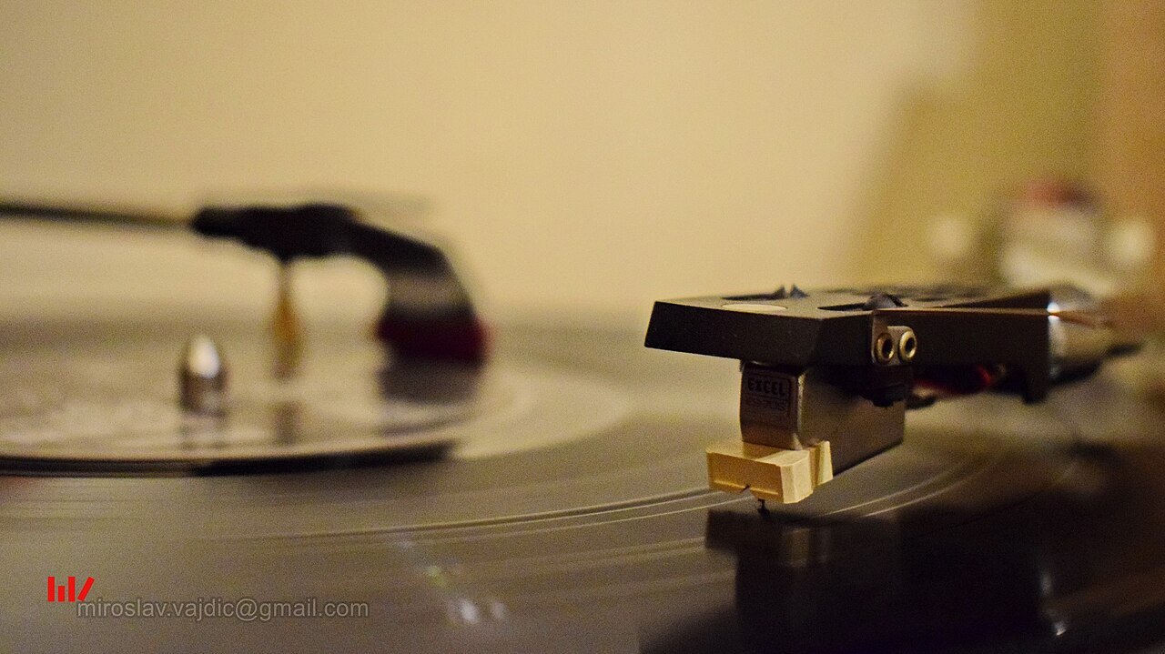 Turntable with an additional record-cleaning arm in the background.