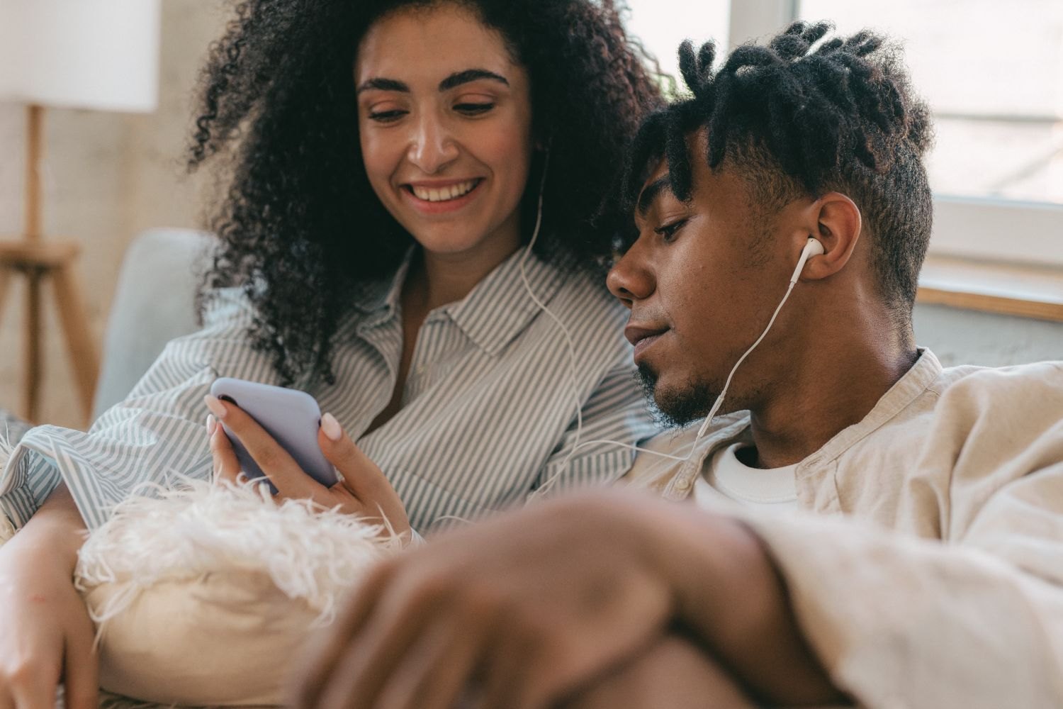 Two people listening together through earphones connected to a smartphone.