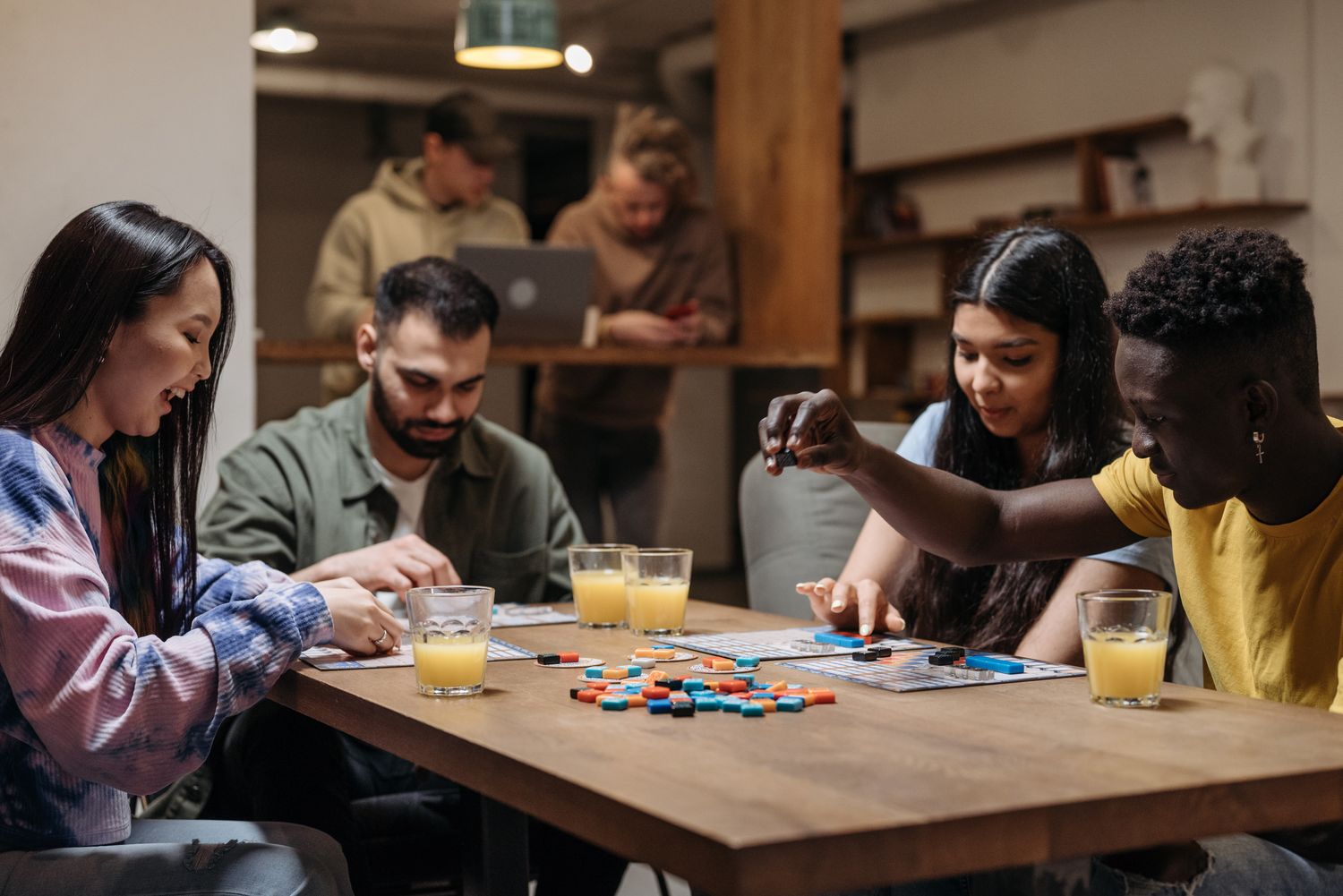 Four people around a table with game boards and coloured pieces.