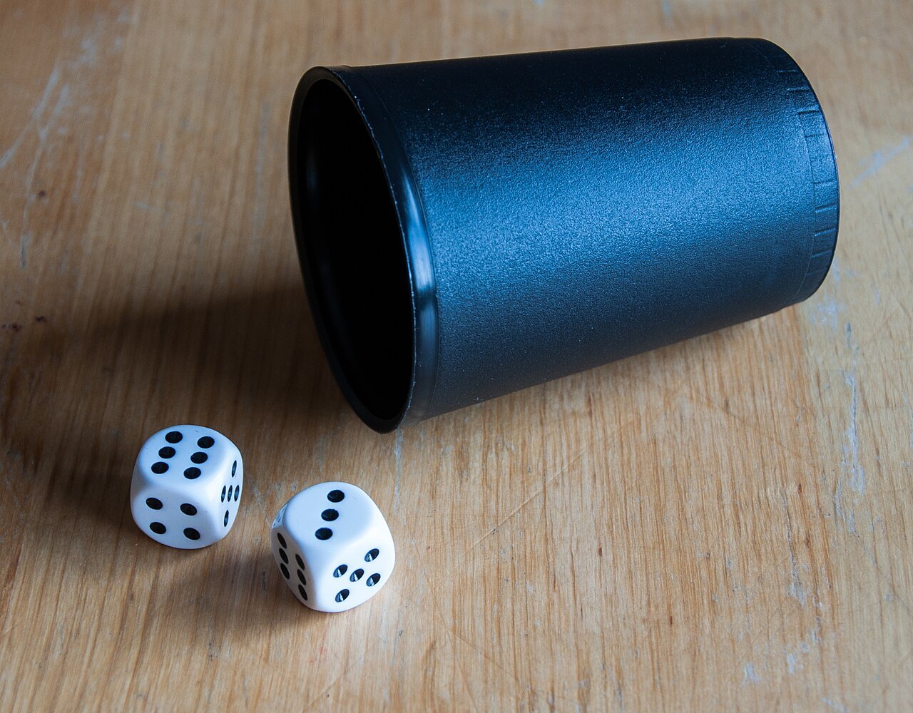 Two dice beside a dice cup.