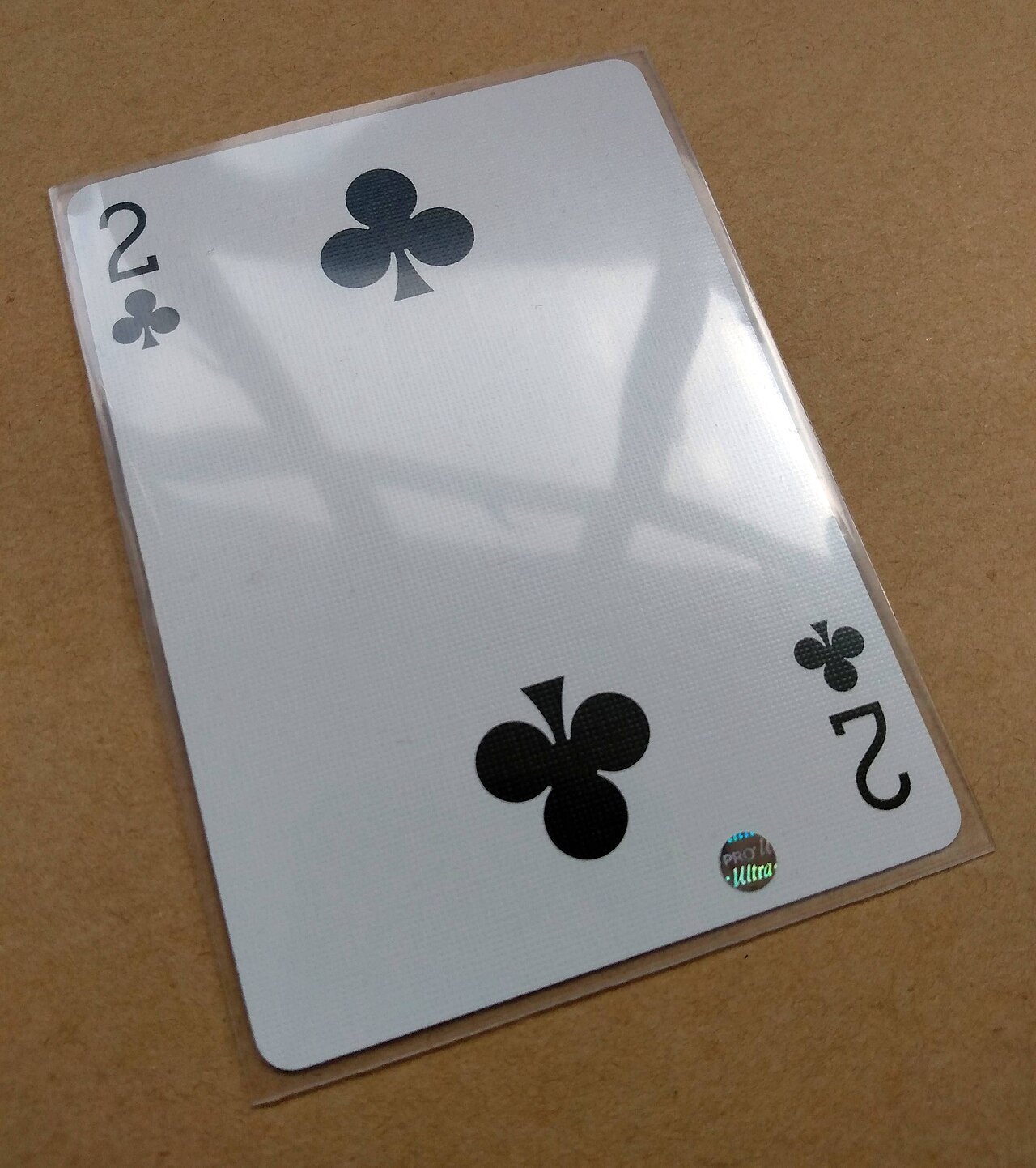 Playing card in a transparent protective sleeve.