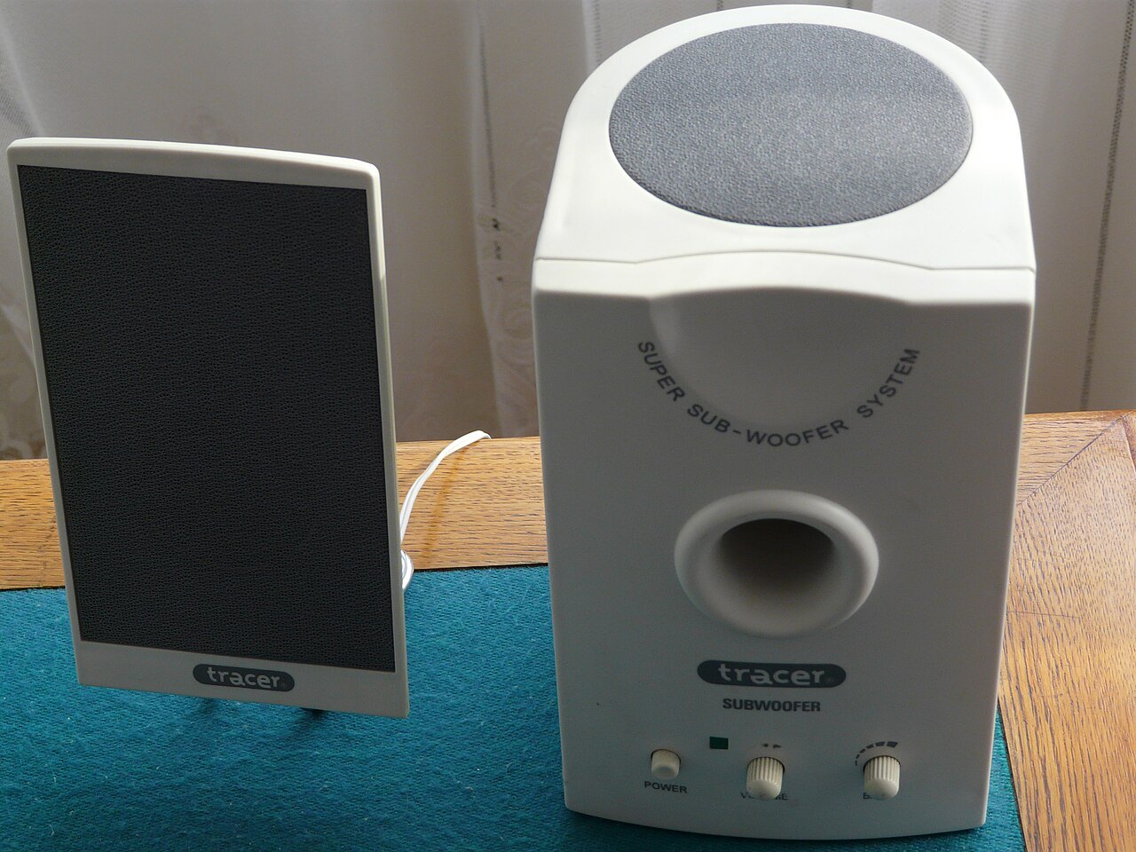 Compact subwoofer beside a satellite speaker.