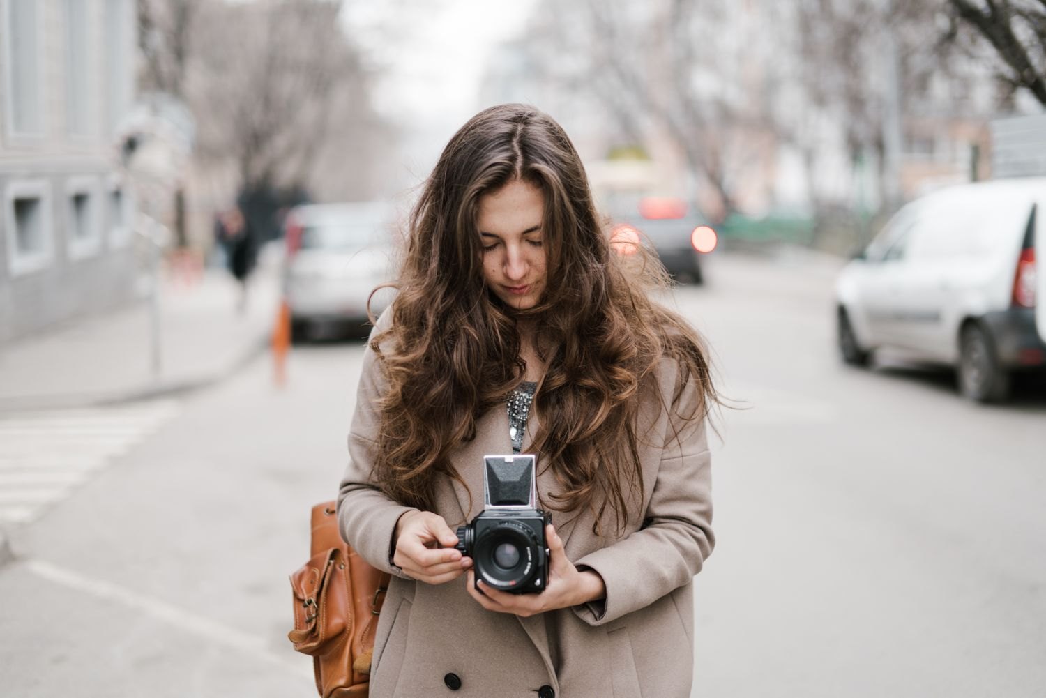 A photographer checks her camera during a walk through the city.