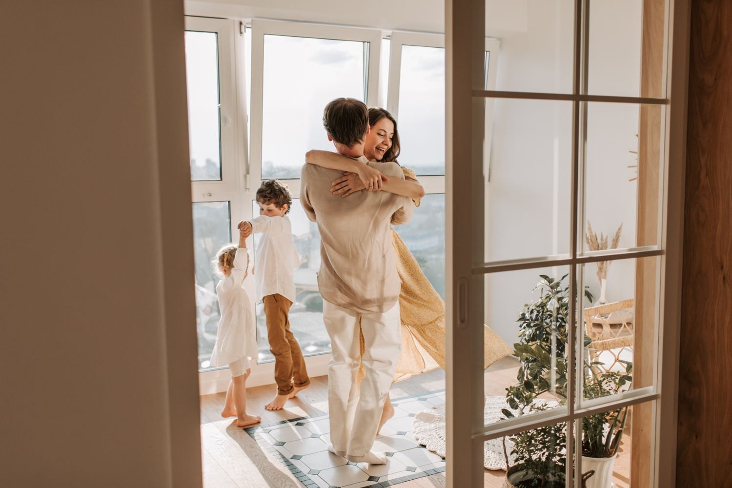Adults and children dance in a bright living space.